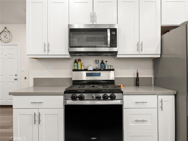 kitchen with appliances with stainless steel finishes, white cabinetry, and wood-type flooring