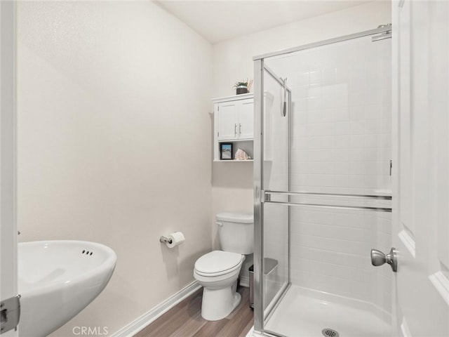 bathroom featuring hardwood / wood-style floors, toilet, walk in shower, and sink