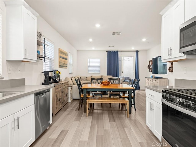 kitchen featuring white cabinets, light wood-type flooring, stainless steel appliances, and sink