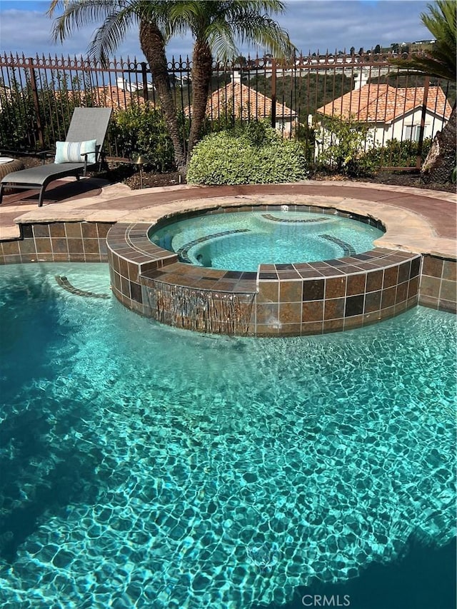 view of pool with pool water feature and an in ground hot tub