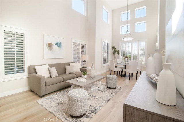 living room with a towering ceiling and light wood-type flooring