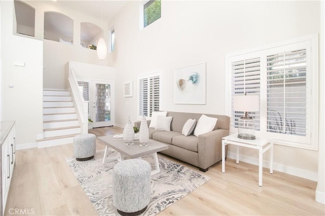 living room with a high ceiling, plenty of natural light, and light hardwood / wood-style flooring