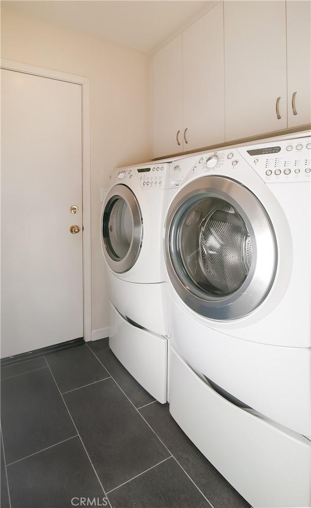 laundry room with cabinets, dark tile patterned floors, and independent washer and dryer