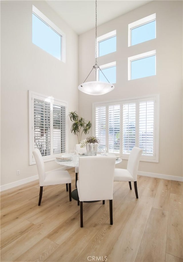 dining space featuring a high ceiling and light wood-type flooring