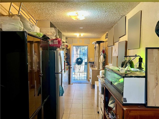 kitchen with stainless steel fridge, light tile patterned flooring, and a textured ceiling