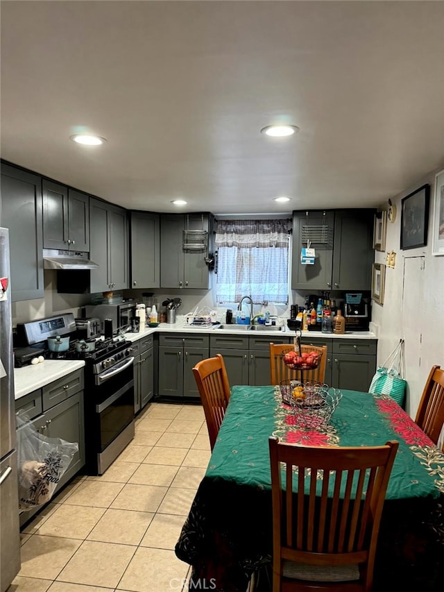 kitchen with appliances with stainless steel finishes, light tile patterned floors, gray cabinetry, and sink