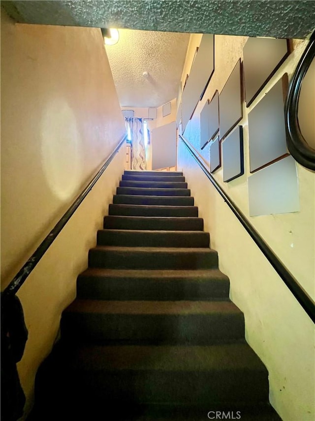 staircase featuring a textured ceiling