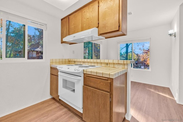 kitchen featuring kitchen peninsula, exhaust hood, tile countertops, light hardwood / wood-style flooring, and white electric range