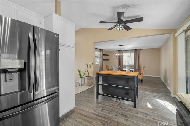 kitchen featuring pendant lighting, hardwood / wood-style floors, lofted ceiling, stainless steel refrigerator with ice dispenser, and white cabinetry