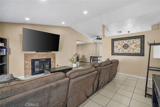 tiled living room featuring lofted ceiling, a tiled fireplace, a textured ceiling, and ceiling fan