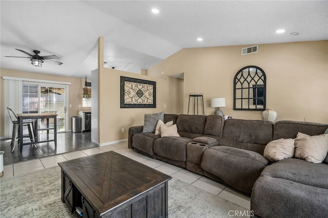 living room featuring ceiling fan, a textured ceiling, lofted ceiling, and light tile patterned flooring