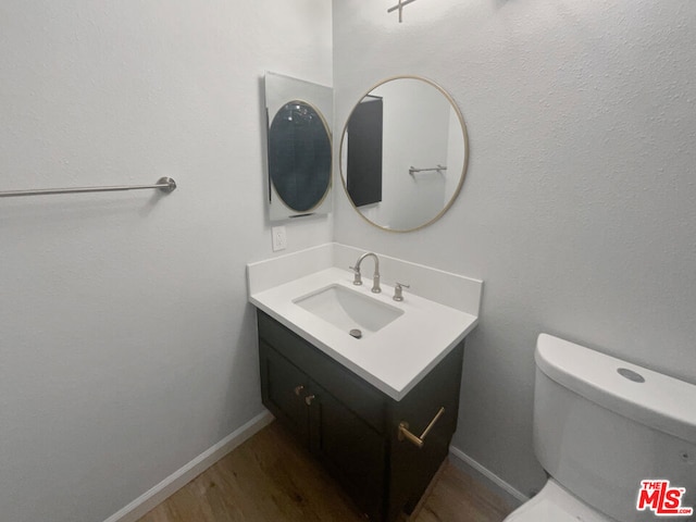 bathroom featuring toilet, vanity, and hardwood / wood-style flooring