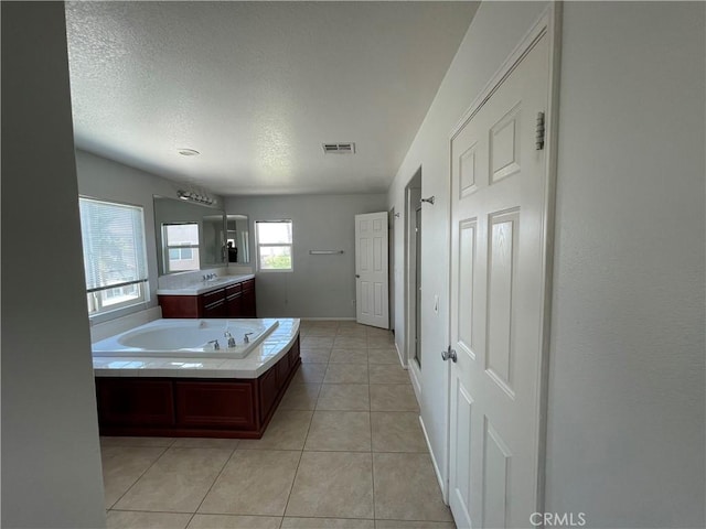 bathroom featuring tile patterned flooring, vanity, a textured ceiling, and a tub