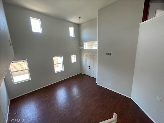 interior space with dark hardwood / wood-style flooring and a towering ceiling