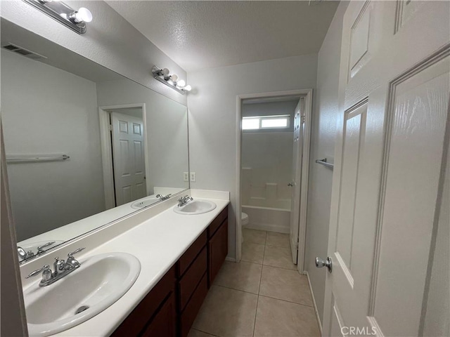 bathroom featuring tile patterned flooring, vanity, a textured ceiling, and toilet