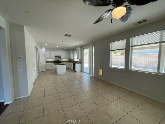 kitchen with white cabinetry, a center island, light tile patterned flooring, and ceiling fan