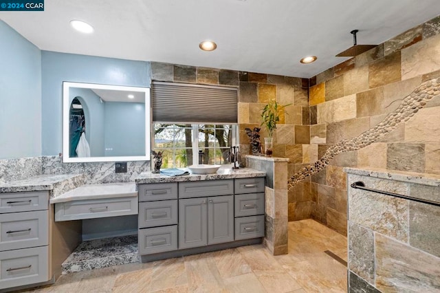 bathroom featuring a tile shower, vanity, and tile walls