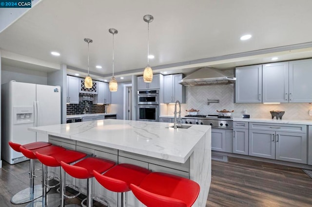 kitchen featuring decorative light fixtures, dark hardwood / wood-style flooring, stainless steel appliances, and a kitchen island with sink