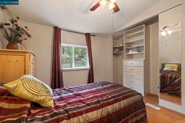 bedroom featuring ceiling fan, light wood-type flooring, and a textured ceiling