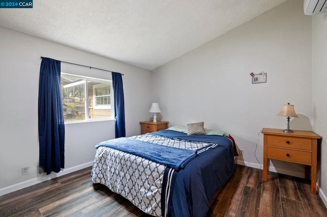 bedroom with a textured ceiling, a wall mounted AC, dark wood-type flooring, and vaulted ceiling