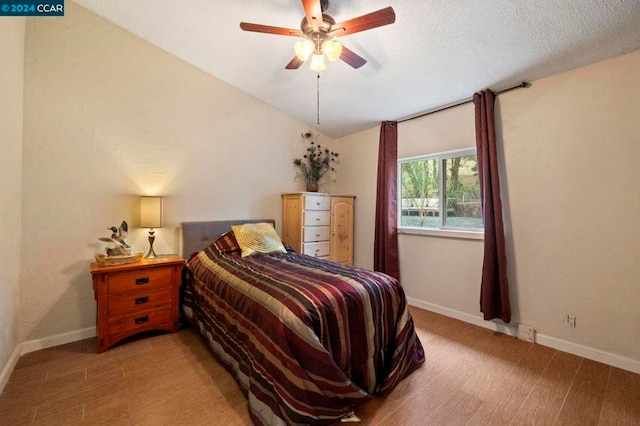 bedroom featuring a textured ceiling, ceiling fan, light hardwood / wood-style floors, and lofted ceiling