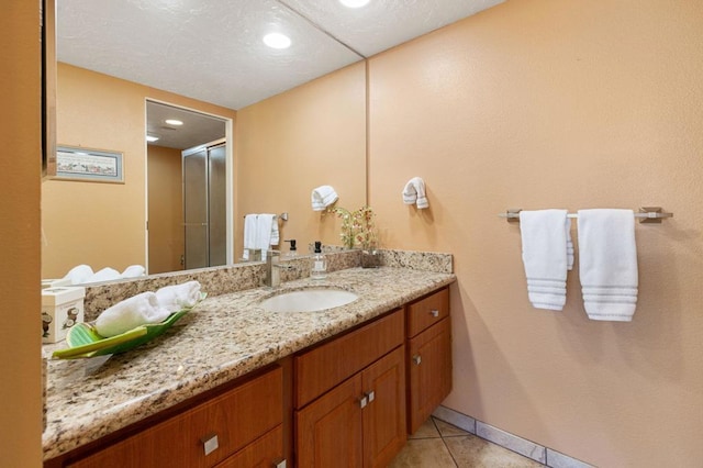 bathroom featuring a shower with shower door, vanity, and tile patterned flooring