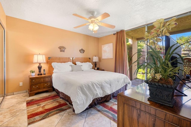 bedroom featuring ceiling fan, light tile patterned floors, and a textured ceiling