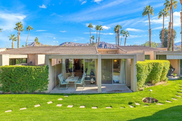 back of house featuring a mountain view, a yard, and a patio