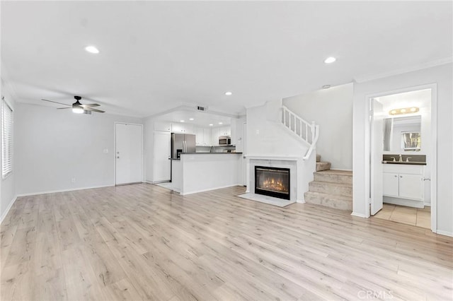 unfurnished living room with light hardwood / wood-style floors, ceiling fan, and ornamental molding