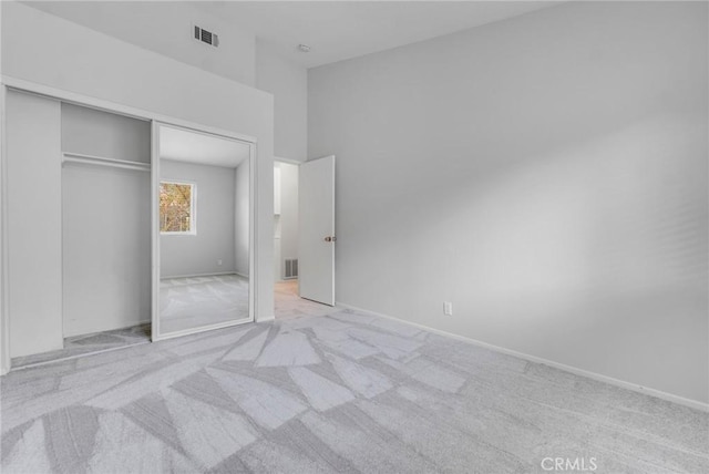 unfurnished bedroom featuring light colored carpet and a closet