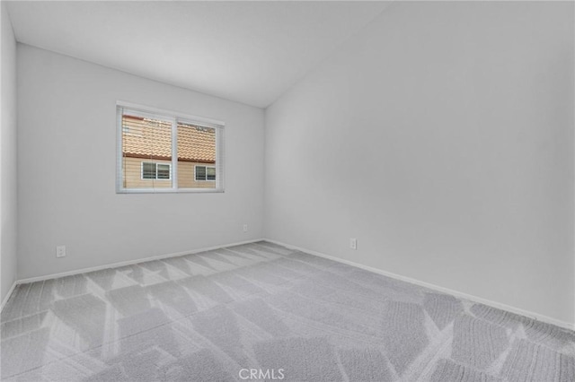 spare room featuring light colored carpet and vaulted ceiling