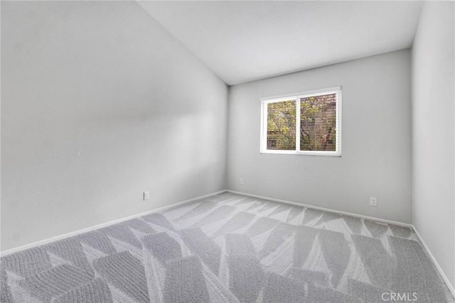 spare room featuring light colored carpet and vaulted ceiling