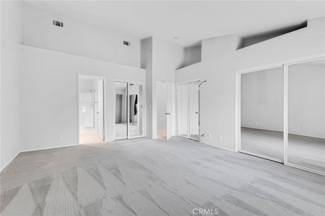 carpeted spare room featuring high vaulted ceiling