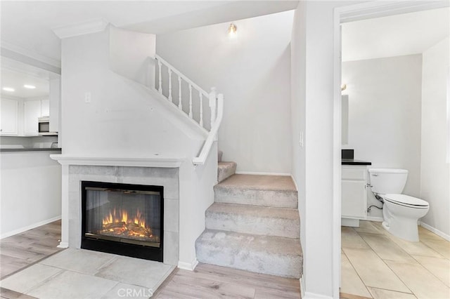 staircase featuring a tile fireplace and hardwood / wood-style floors