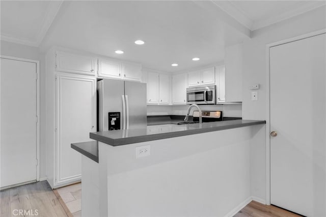 kitchen with kitchen peninsula, stainless steel appliances, white cabinets, and light hardwood / wood-style floors