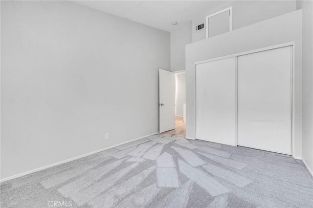 unfurnished bedroom with light carpet and a closet