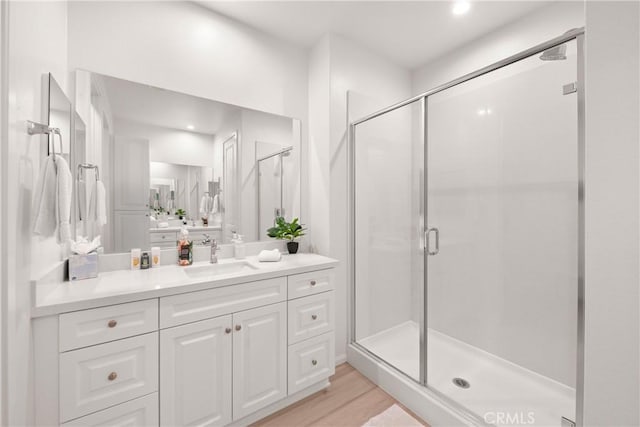 bathroom featuring hardwood / wood-style flooring, vanity, and a shower with door