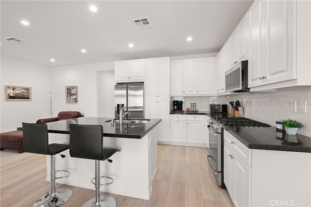 kitchen featuring stainless steel appliances, a kitchen island with sink, and white cabinets