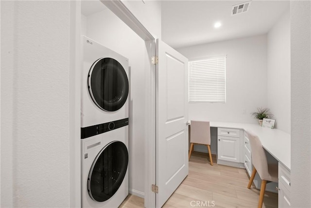 laundry room featuring stacked washer and clothes dryer and light hardwood / wood-style flooring