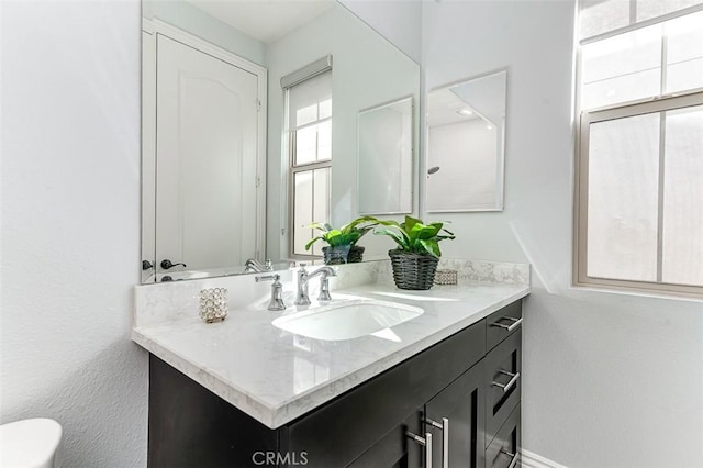 bathroom featuring toilet, baseboards, and vanity