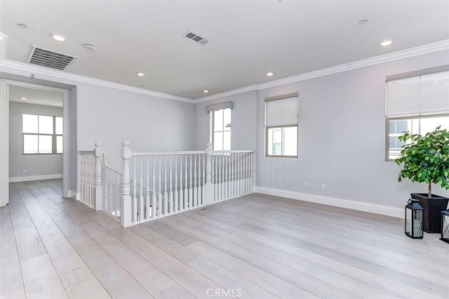 empty room featuring ornamental molding, a wealth of natural light, visible vents, and light wood-style flooring