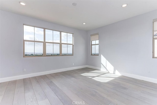 empty room featuring recessed lighting, wood finished floors, and baseboards