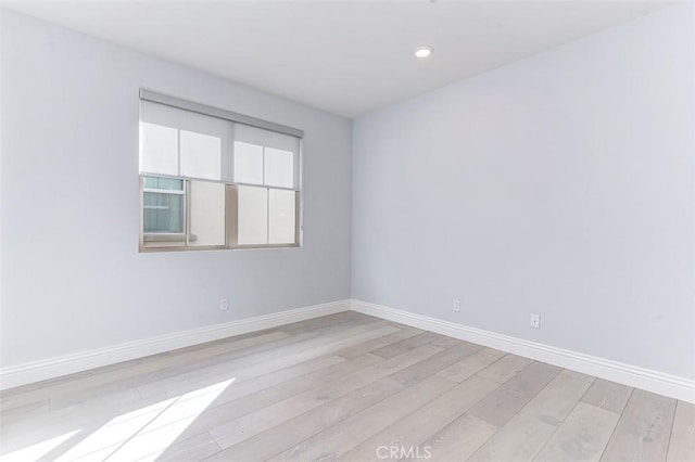 spare room featuring recessed lighting, light wood-style flooring, and baseboards