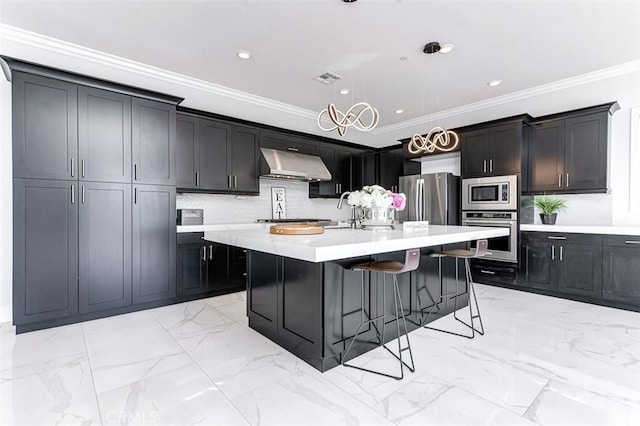 kitchen with a breakfast bar area, appliances with stainless steel finishes, marble finish floor, light countertops, and under cabinet range hood