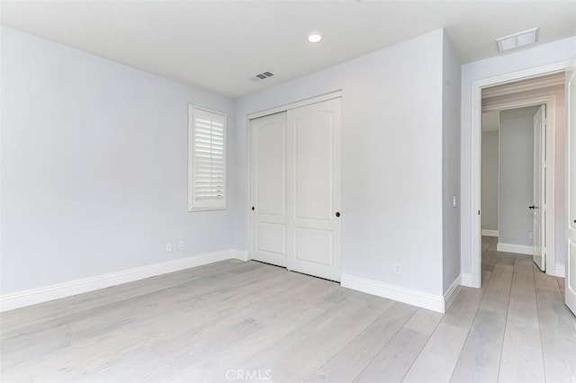 unfurnished bedroom featuring light wood-style flooring, a closet, visible vents, and baseboards