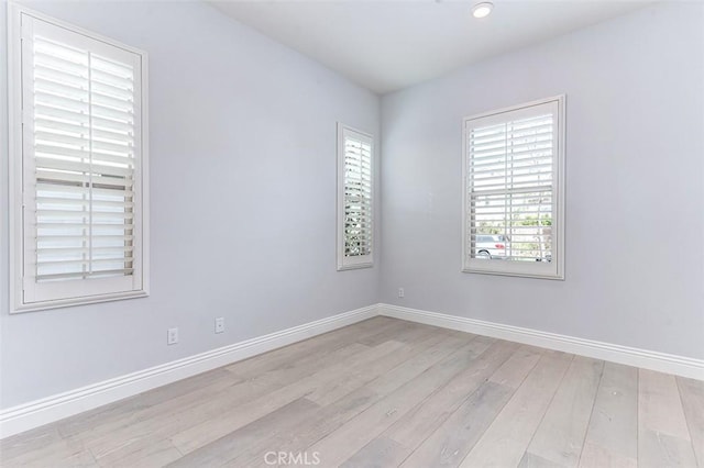 spare room featuring light wood-type flooring, a wealth of natural light, and baseboards