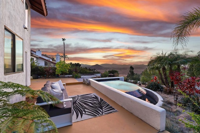 patio terrace at dusk featuring a mountain view and an outdoor living space