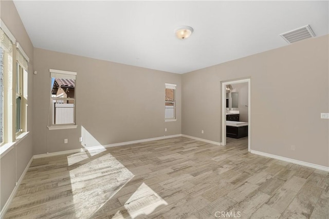 spare room featuring light wood-type flooring and plenty of natural light