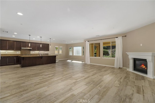 unfurnished living room featuring sink and light hardwood / wood-style floors