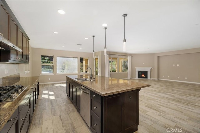kitchen featuring a center island with sink, sink, appliances with stainless steel finishes, and dark brown cabinetry